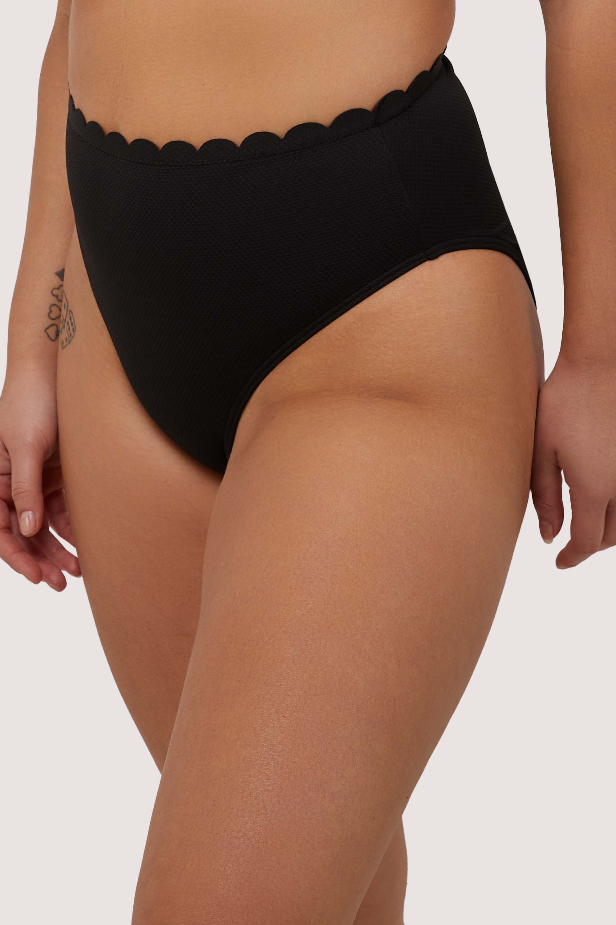 model wears black scalloped high waist bikini bottoms