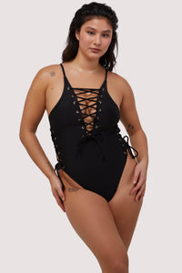 Model wears black lace-up plunge neckline swimsuit