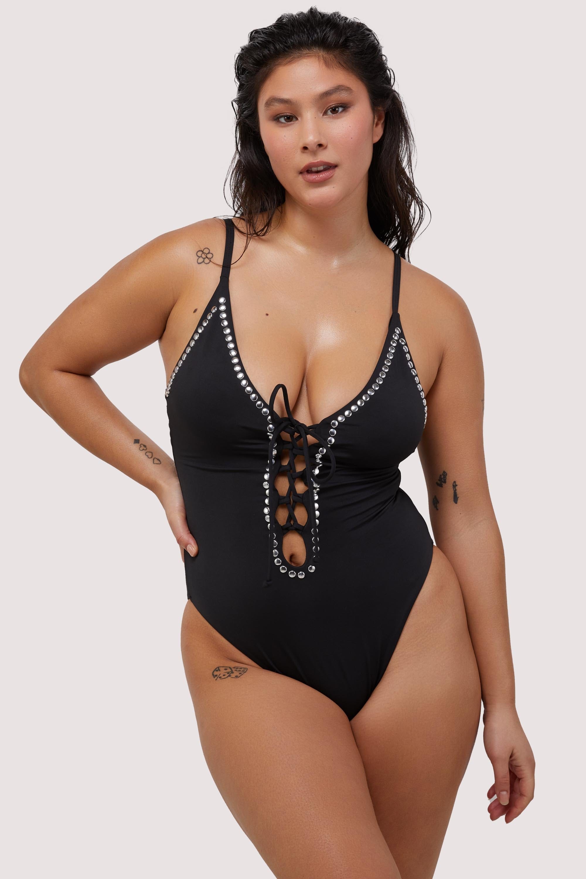Model wears black plunge neckline lace-up swimsuit with silver studs