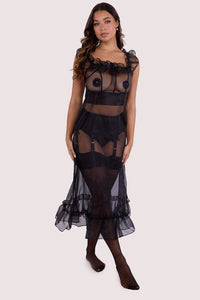 Model wears a black sheer organza dress with a fitted design, ruffled details, and a cinched waist for a feminine look.