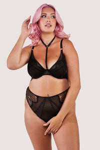 Black lacy fishnet plunge bra with gold hardware, worn with a matching brief.