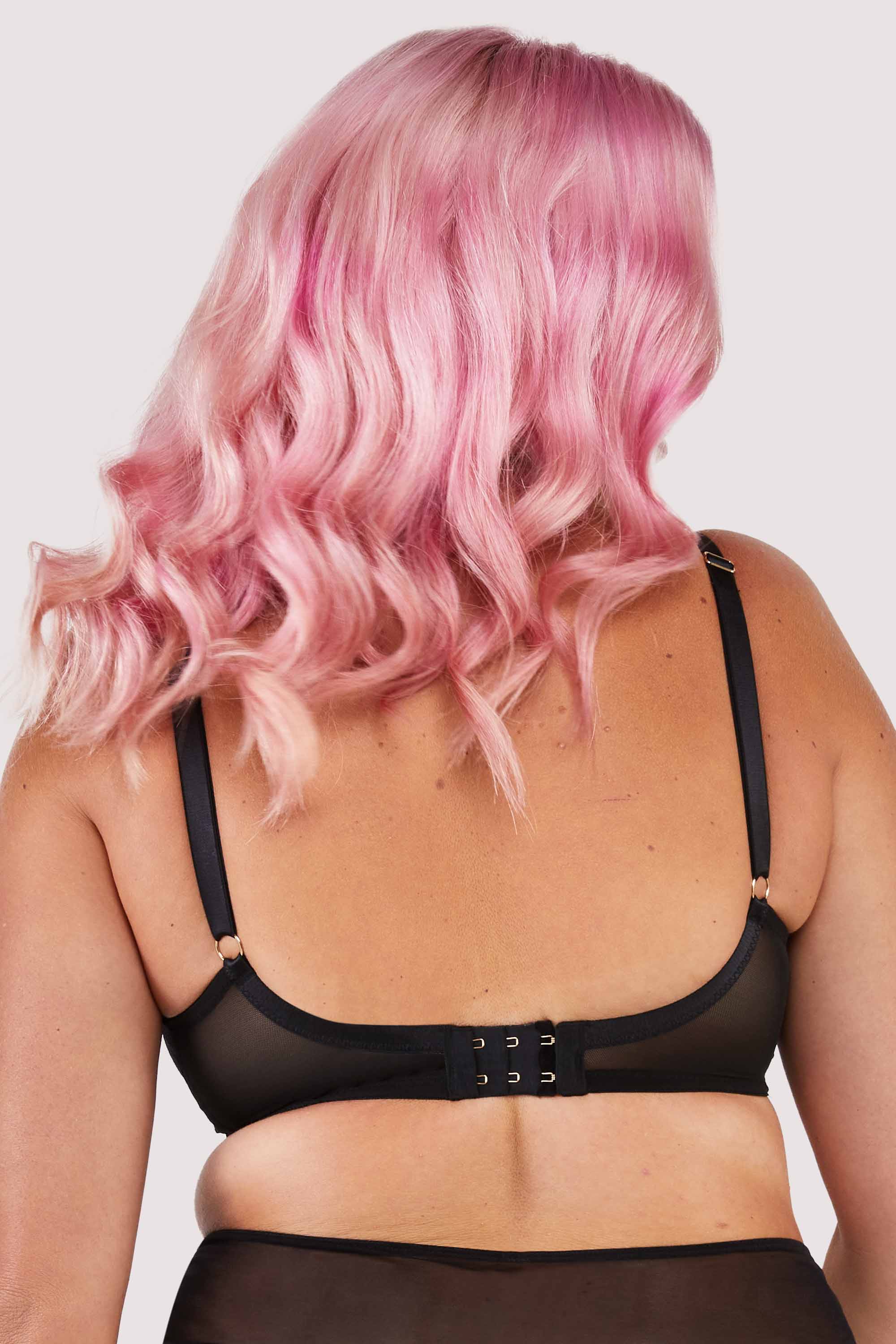 Back view of a black lacy fishnet plunge bra with gold hardware.