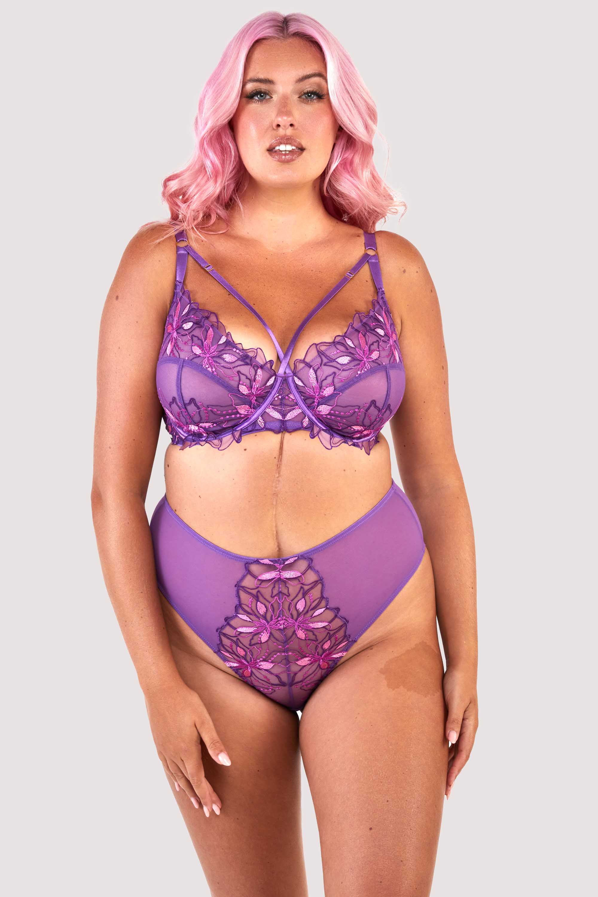 Mesh purple thong with an embroidered pink and purple panel in the front, worn with a matching bra, worn with a matching bra.