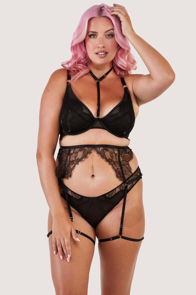 Black fishnet and lace ensemble, featuring a bra with harness detailing around the neck, a matching suspender and a black brief.