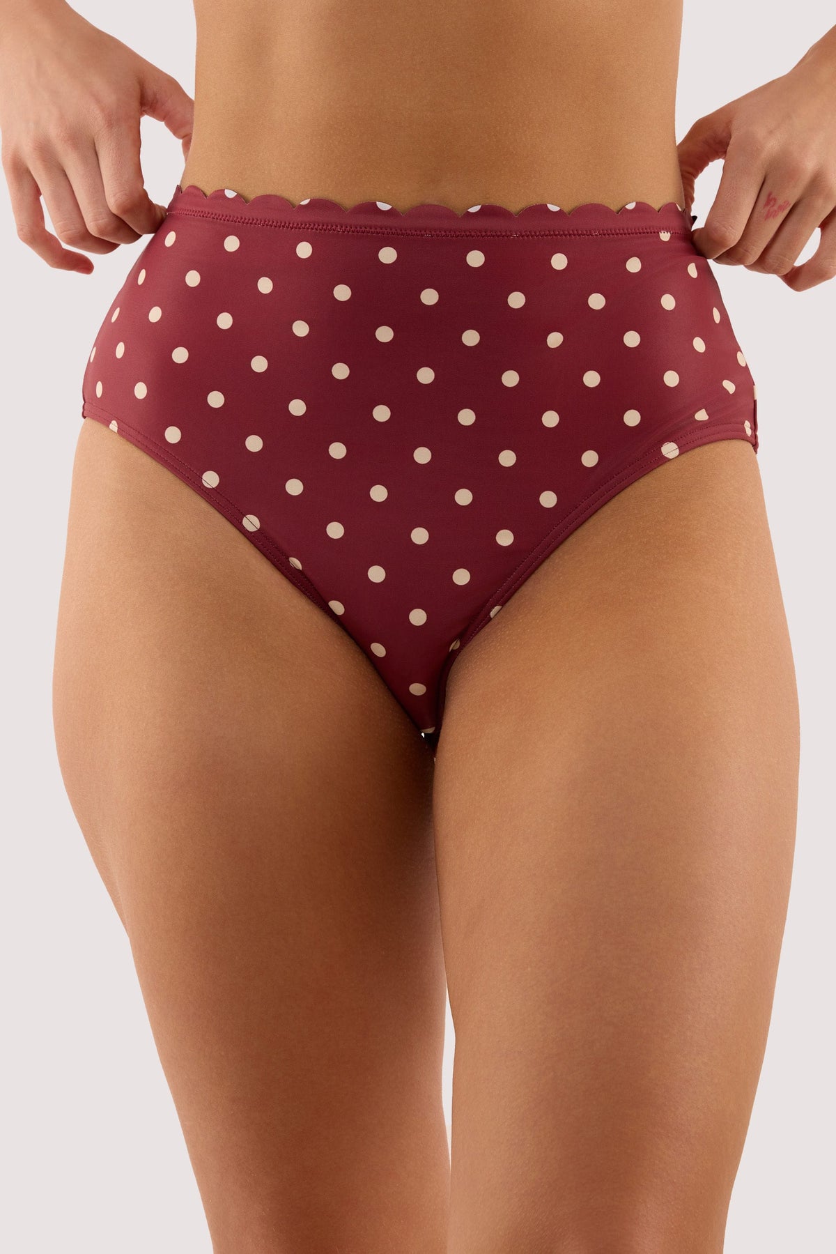 Model wears a hazel wine spot high waist bikini brief and high waist, high-leg style and full coverage featuring lined gusset.