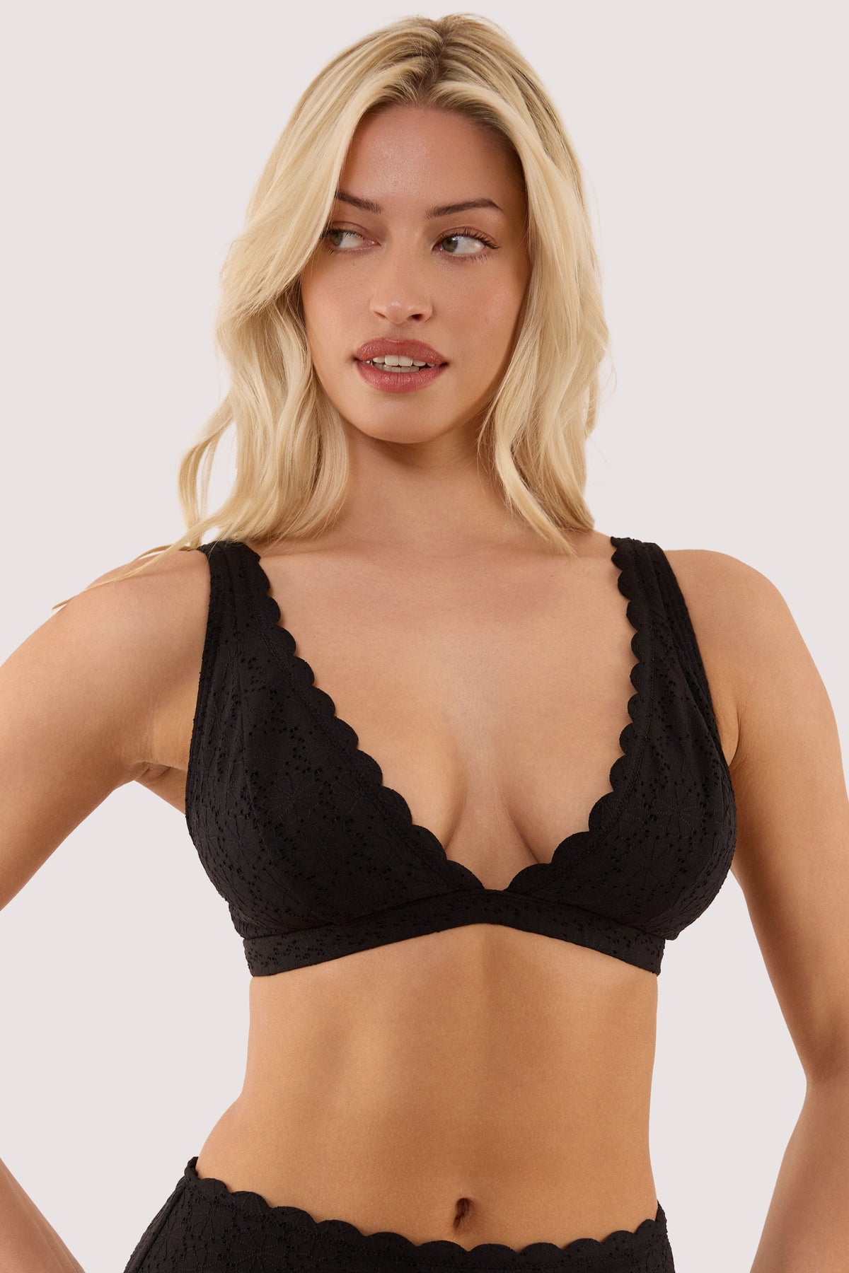 Model wears a nikki black broderie scallop high apex bikini top with scallop trims and a broderie fabric.