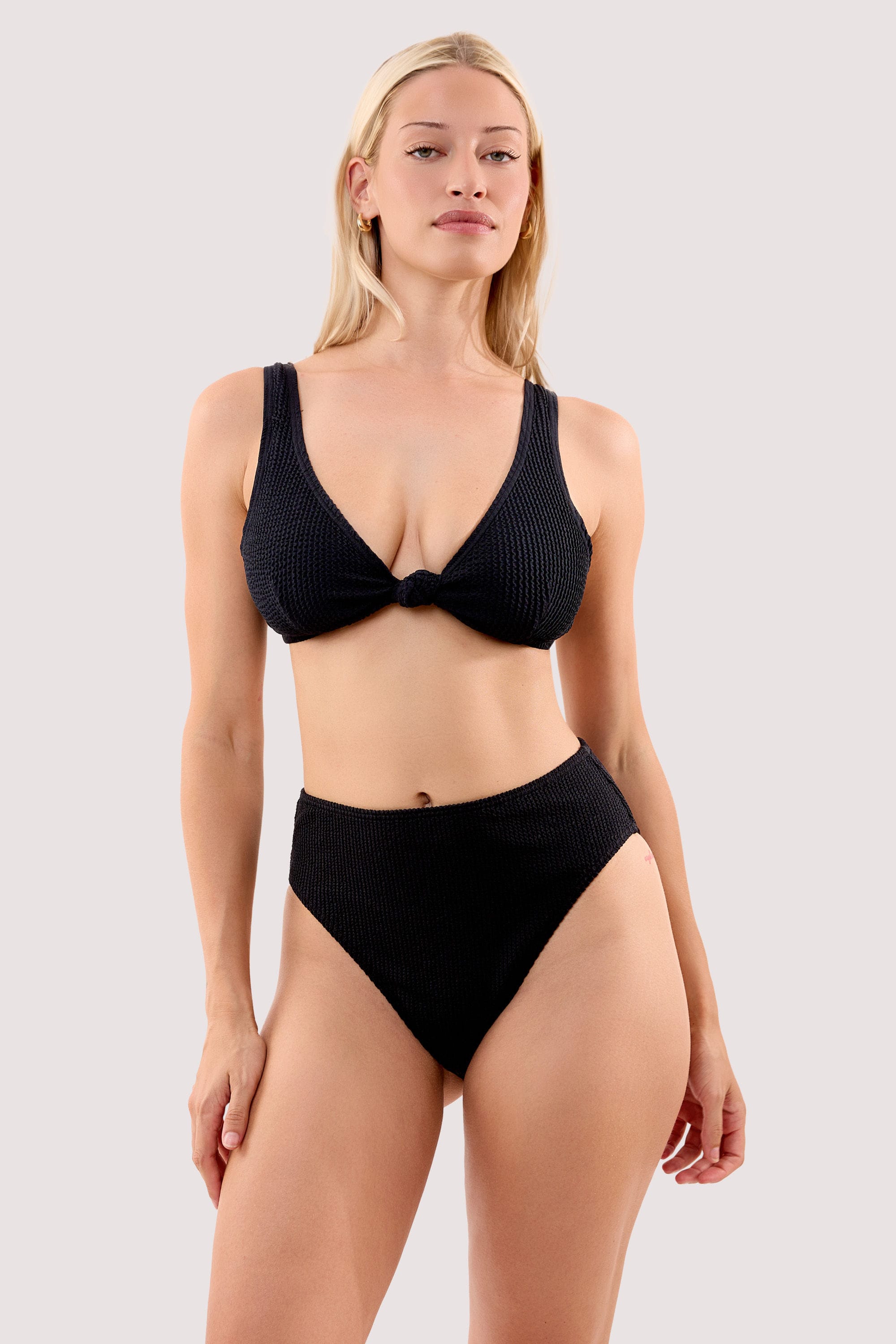 Model wears a selene black crinkle high waist bikini bottom with a matching bikini top.