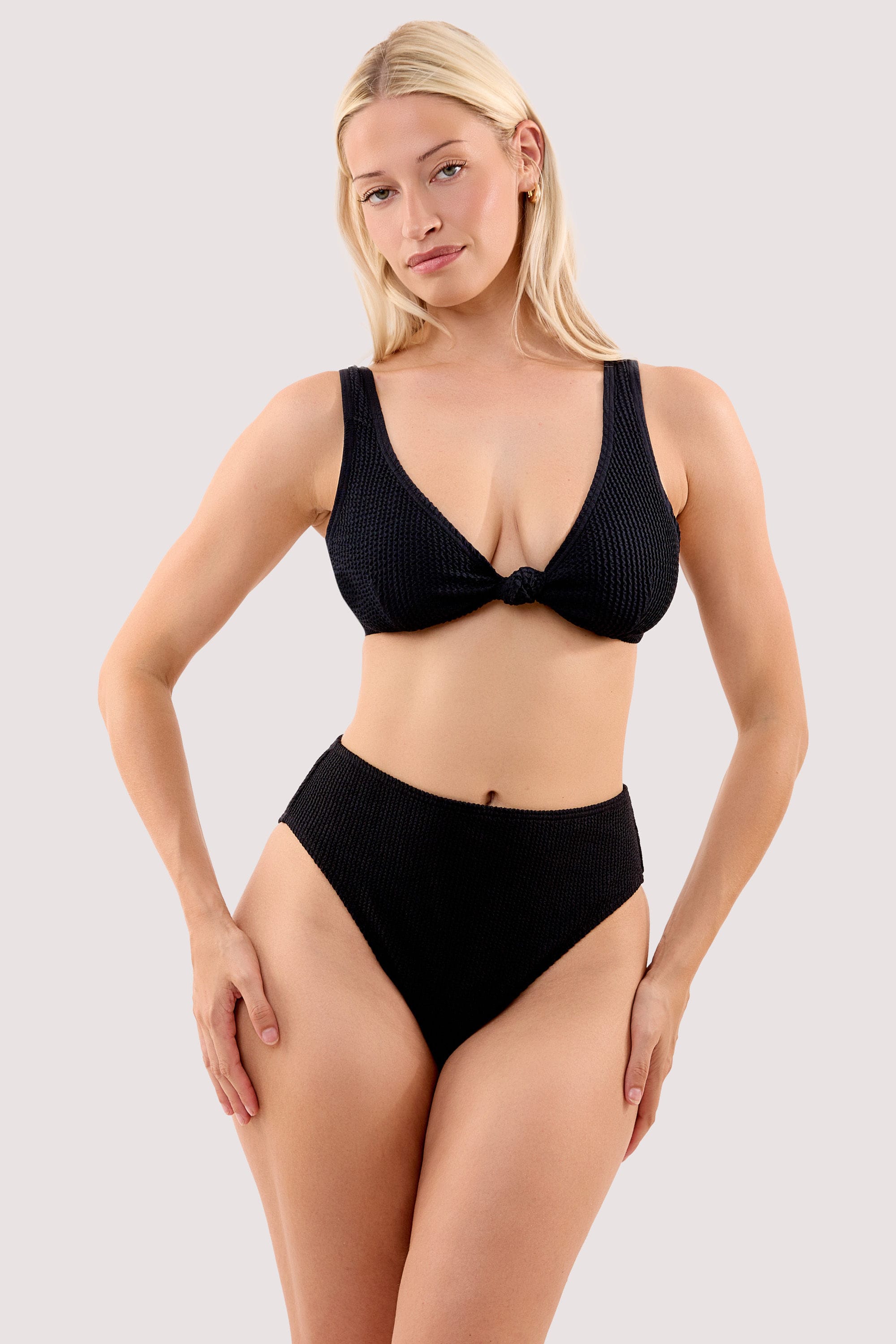 Model wears a selene black crinkle knot front bikini top with a matching high waist bikini bottom.