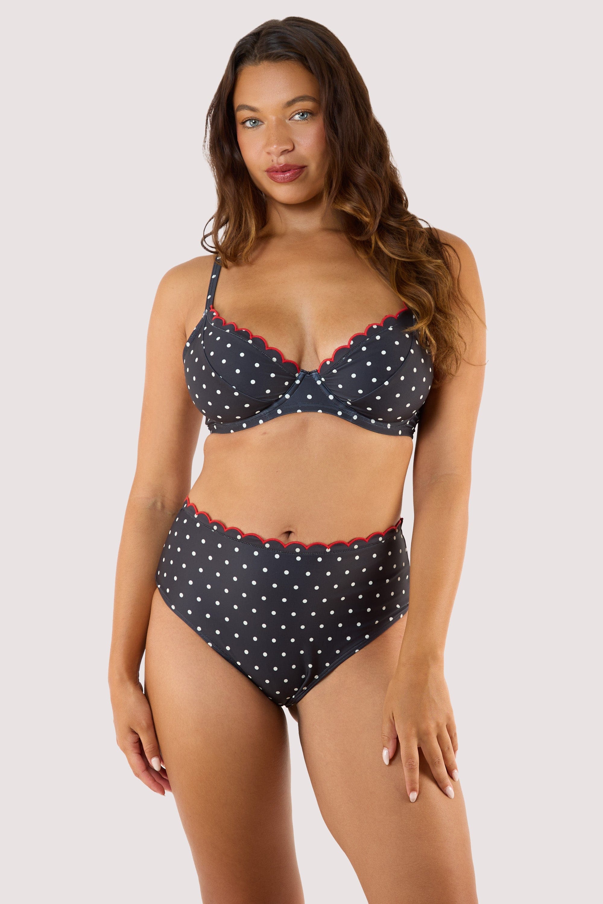 Model Wearing a black polka dot bikini top, showcasing playful pin-up style with red scalloped edges and high-waist design.