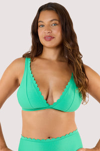 Model Wearing a jade green bikini top featuring scalloped edges and a high-apex plunge, complemented by adjustable straps.