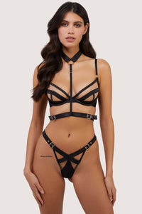 Model wears black plunge bra with choker harness and matching thong