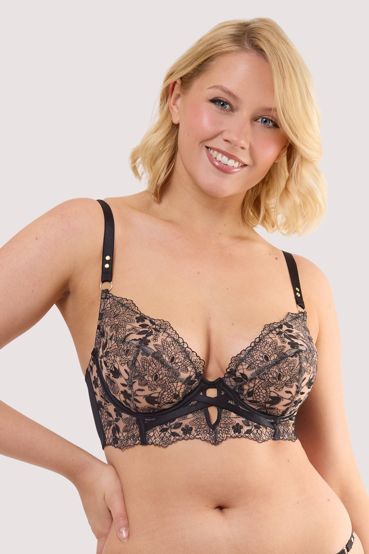 Model wears a cindy black floral embroidery longline bra featuring black mesh with floral embroidery and scalloped lace trim and satin straps.