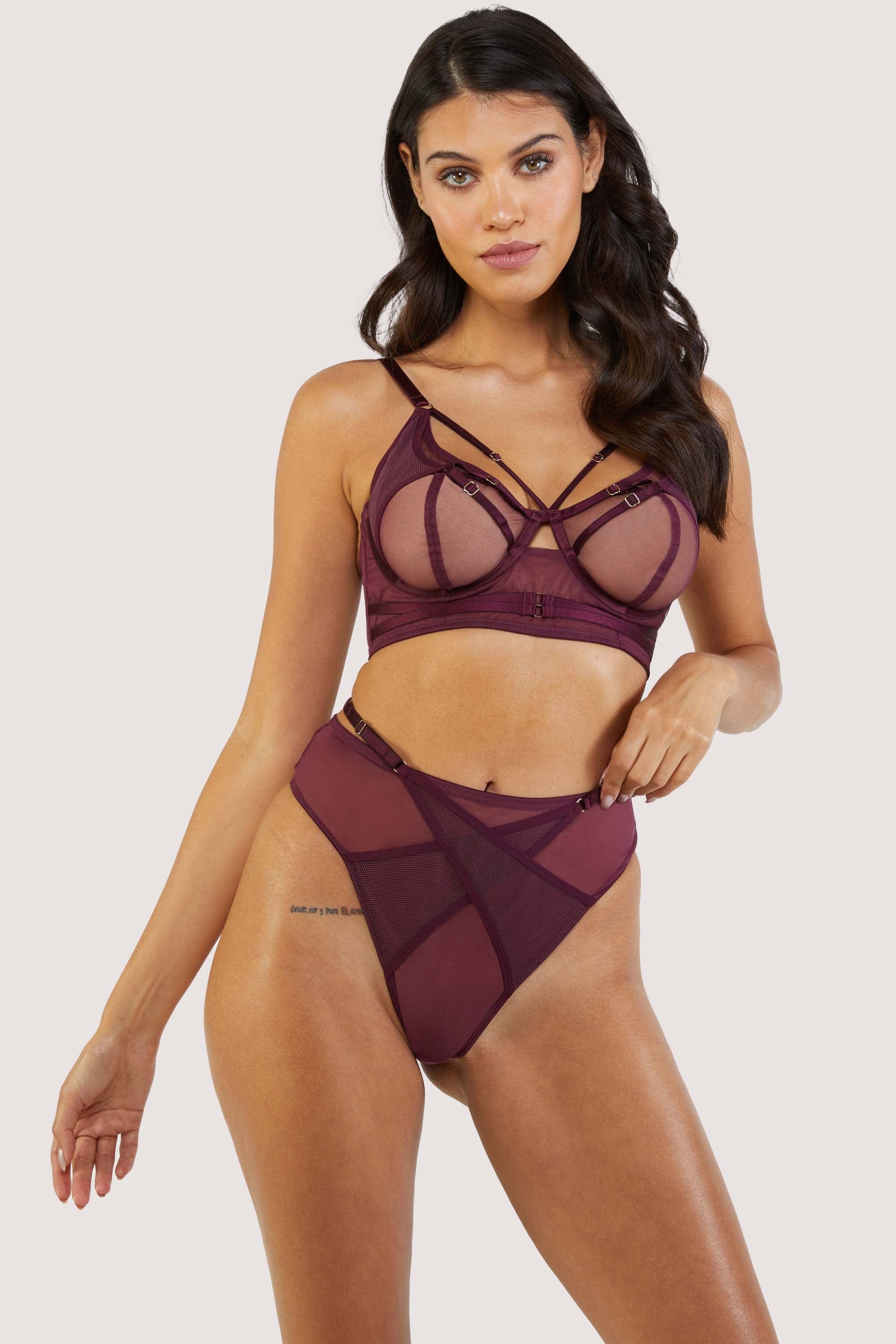 Harness style bra with mesh overlay and visible gold hardware in a deep wine red/purple, worn with a matching brief..