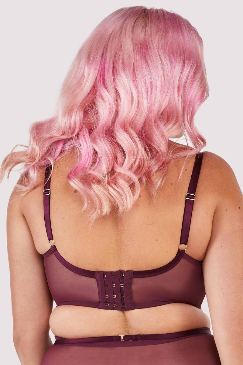Back view of a harness style bra with mesh overlay and visible gold hardware in a deep wine red/purple.
