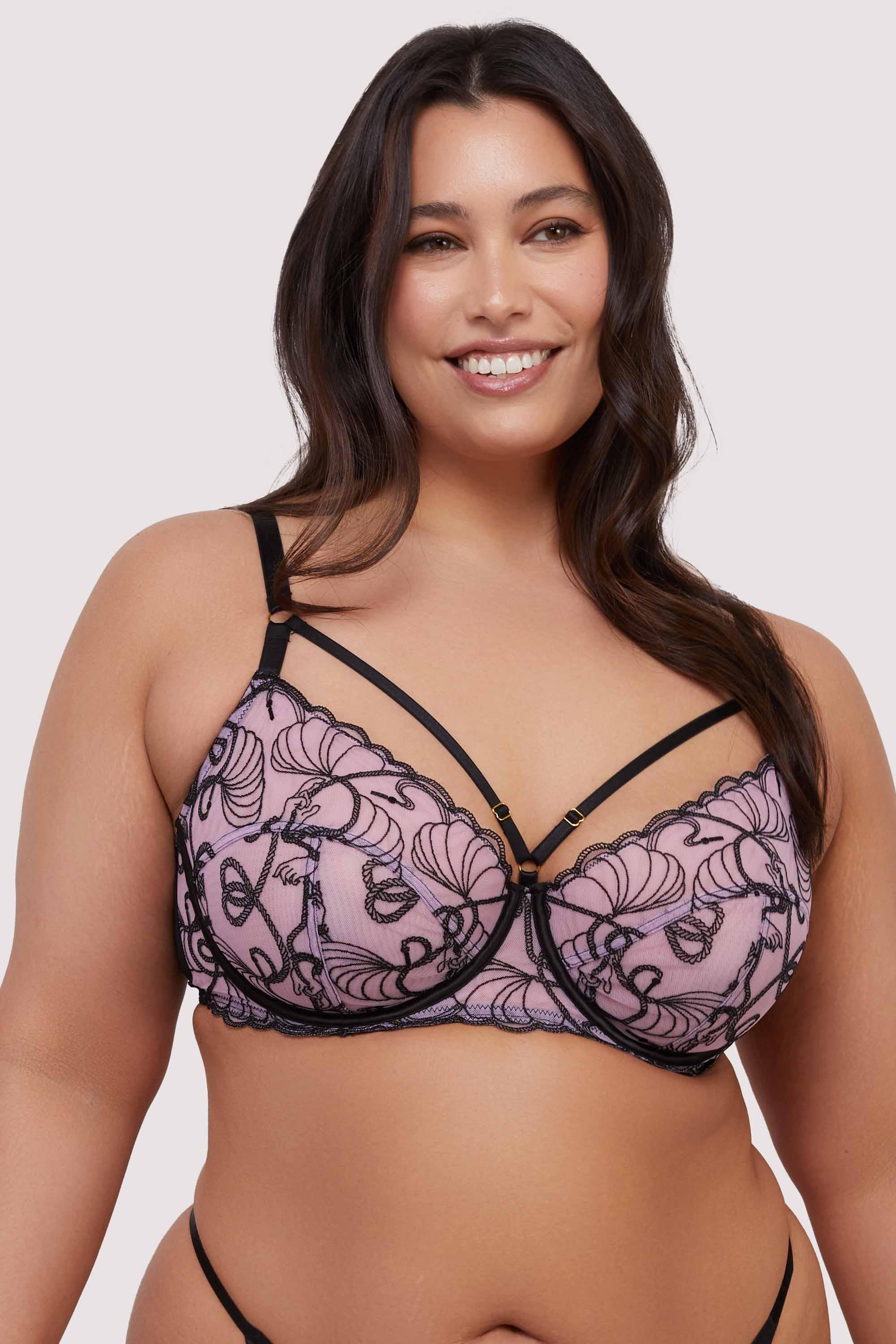 model wears pink and black embroidered bra with straps