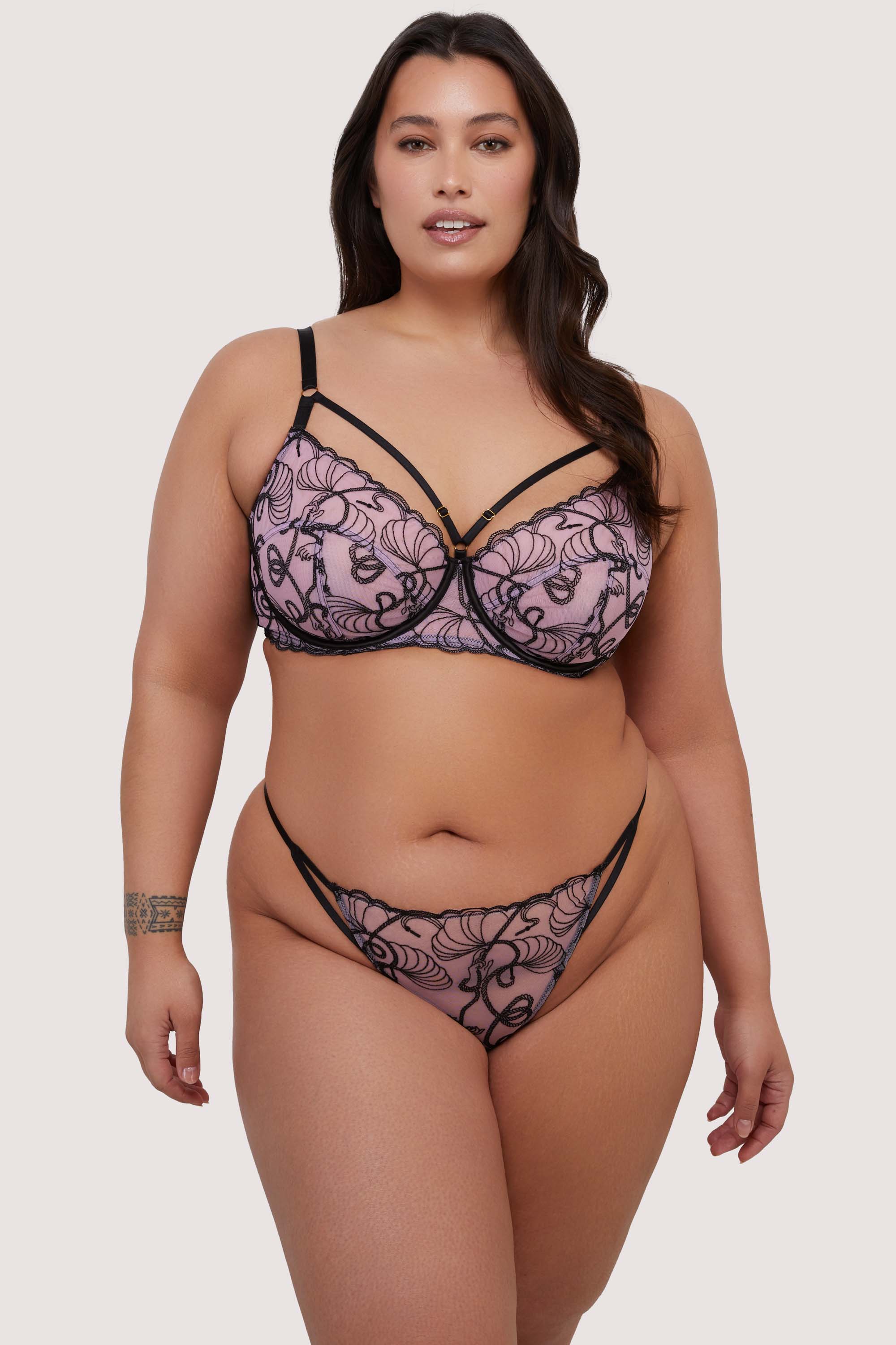 model wears pink and black embroidered bra and thong set with straps
