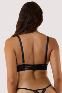 Model showing back of a sheer black bra, featuring floral embroidery and scalloped lace edges.