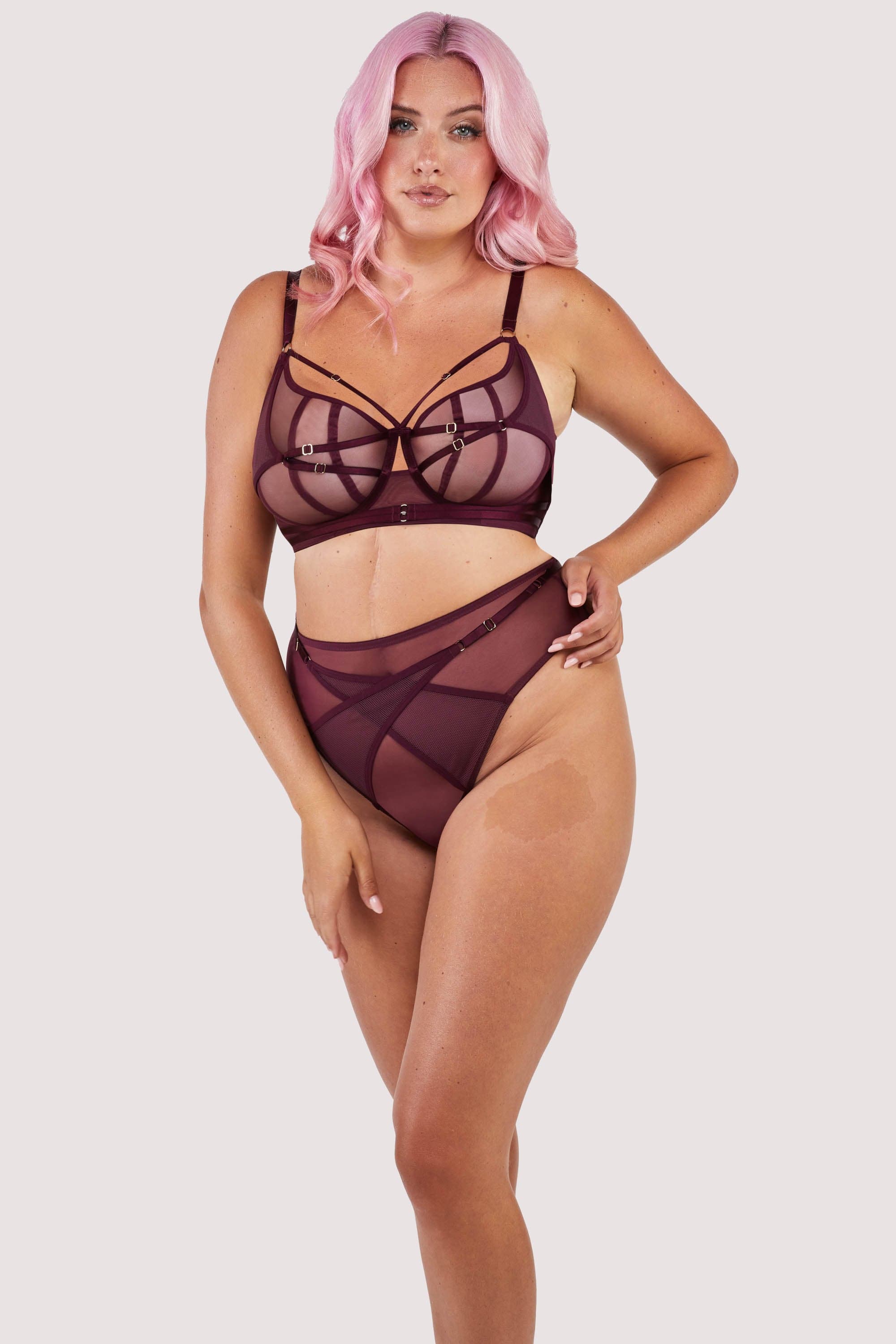 Harness style brief with mesh overlay and visible gold hardware in a deep wine red/purple, worn with a matching bra.