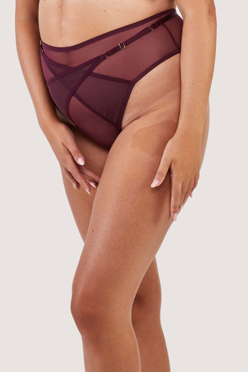 Harness style brief with mesh overlay and visible gold hardware in a deep wine red/purple.