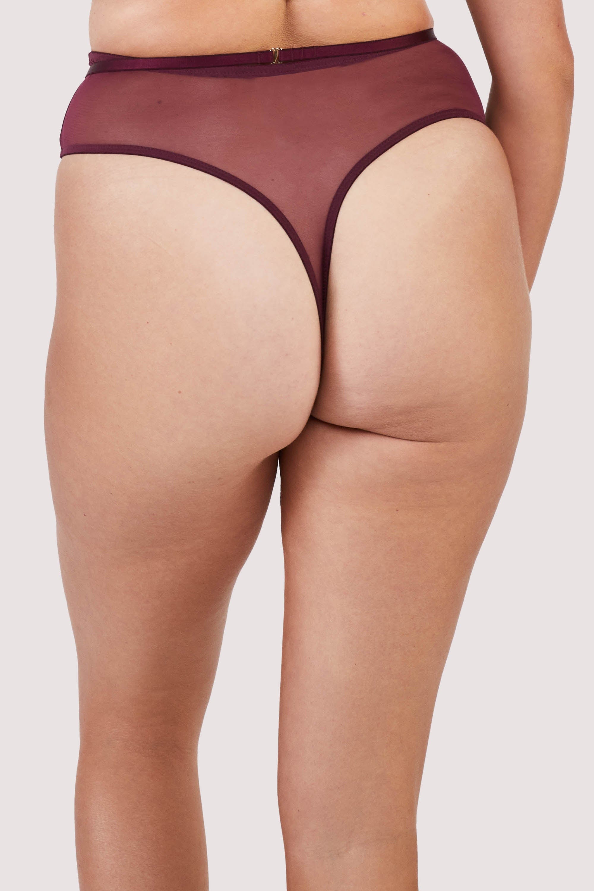 Back view of harness style thong with mesh overlay and visible gold hardware in a deep wine red/purple.