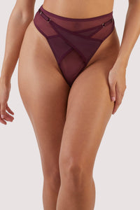 Harness style crossover thong with mesh overlay and visible gold hardware in a deep wine red/purple.