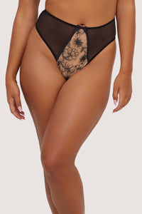 Model wears a black mesh high-waist thong with floral embroidery details