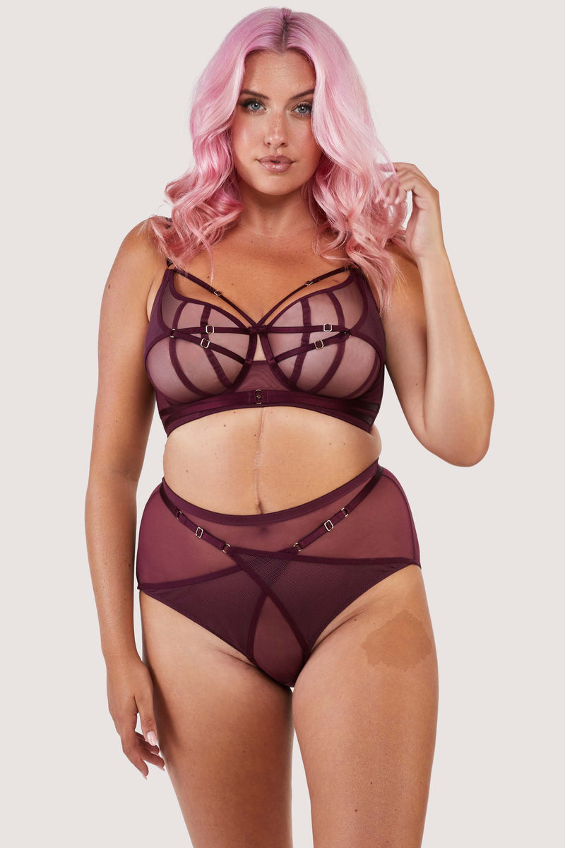 Harness style bra and brief with mesh overlay and visible gold hardware in a deep wine red/purple.