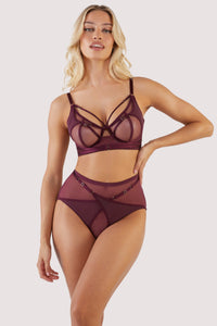 Harness style bra and brief with mesh overlay and visible gold hardware in a deep wine red/purple.