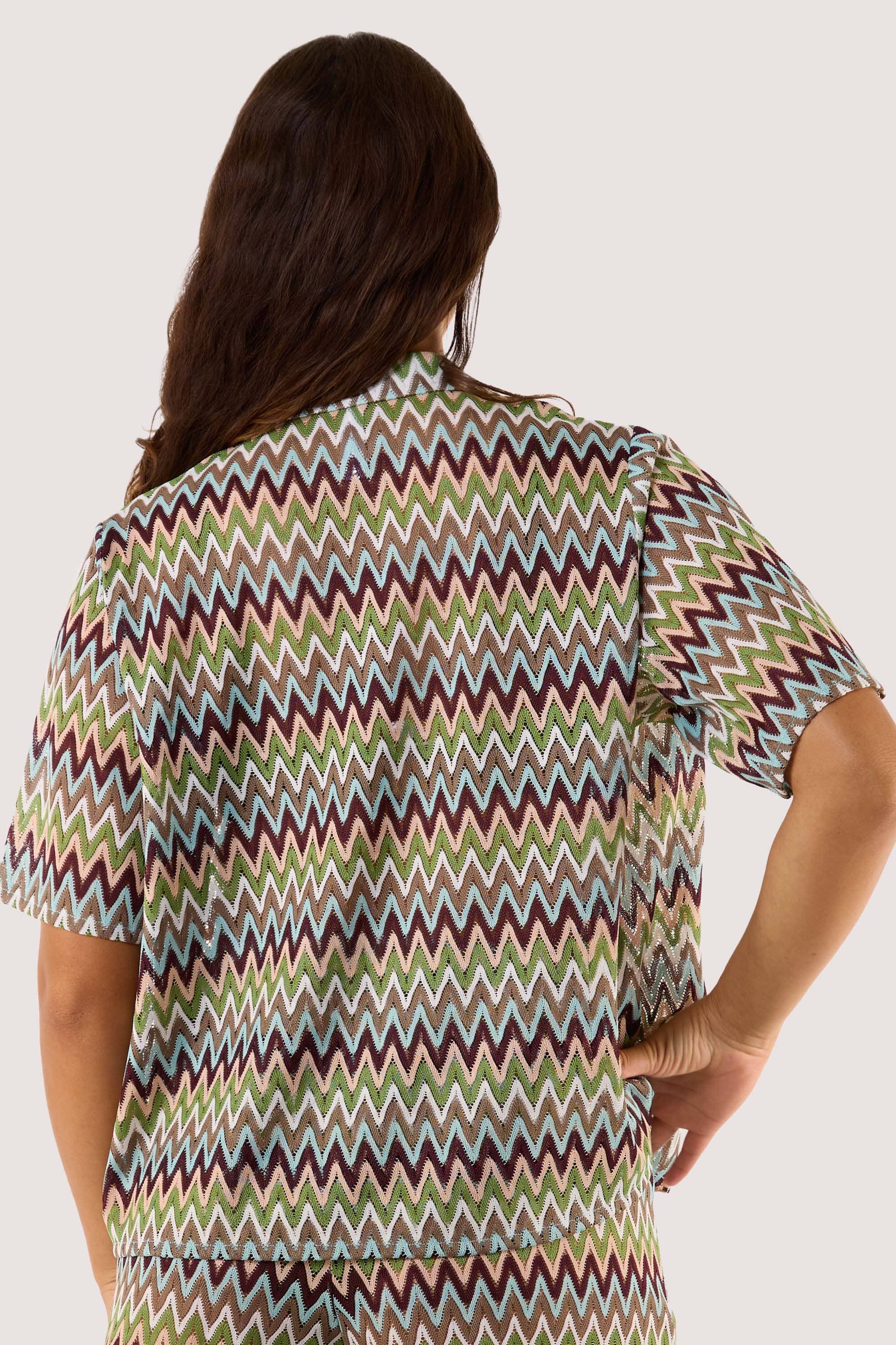 Model Back view of wearing a chevron print shirt, highlighting its breezy crochet fabric and stylish zig-zag pattern.