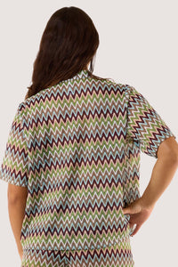 Model Back view of wearing a chevron print shirt, highlighting its breezy crochet fabric and stylish zig-zag pattern.