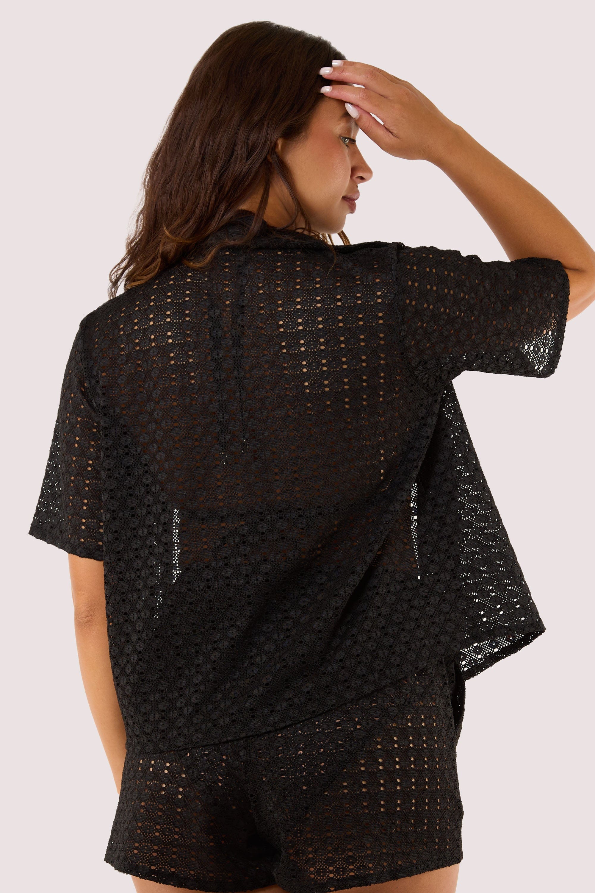 Model Back view of a black crochet beach shirt with short sleeves, a collar, and a relaxed fit, perfect for resort wear.