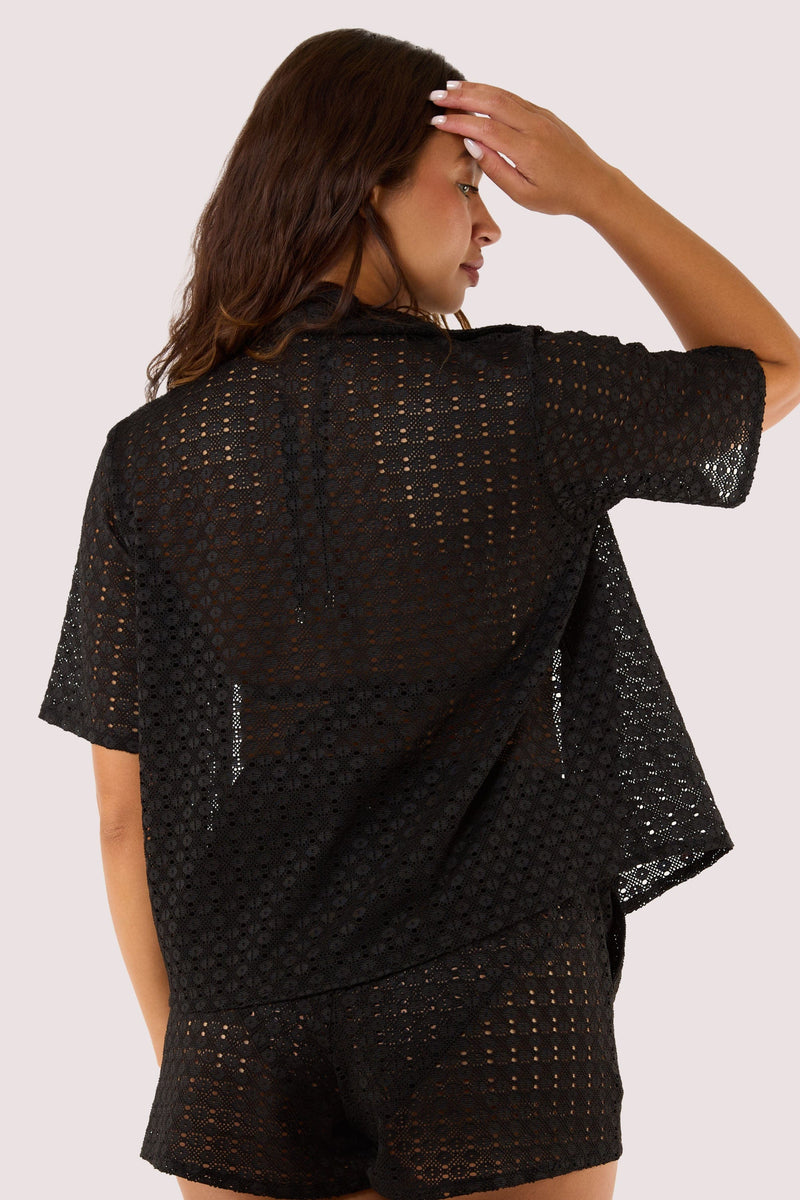 Model Back view of a black crochet beach shirt with short sleeves, a collar, and a relaxed fit, perfect for resort wear.