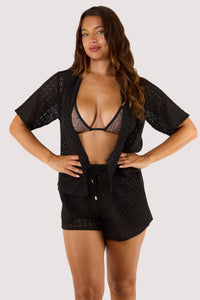 Model in a black swimsuit paired with textured crochet beach shorts, featuring an adjustable waist tie and relaxed fit.