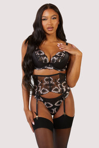 Waspie with panelled black mesh and satin, delicate black and pale pink floral embroidery and black bows on each of the 4 suspender straps worn with a matching thong and plunge bra.