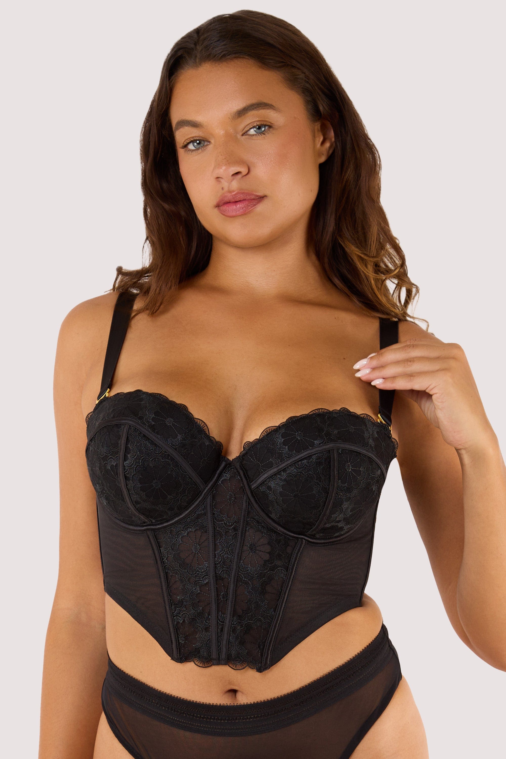 Model wears black embroidered mesh boned  bustier with removable shoulder straps and underwire cups