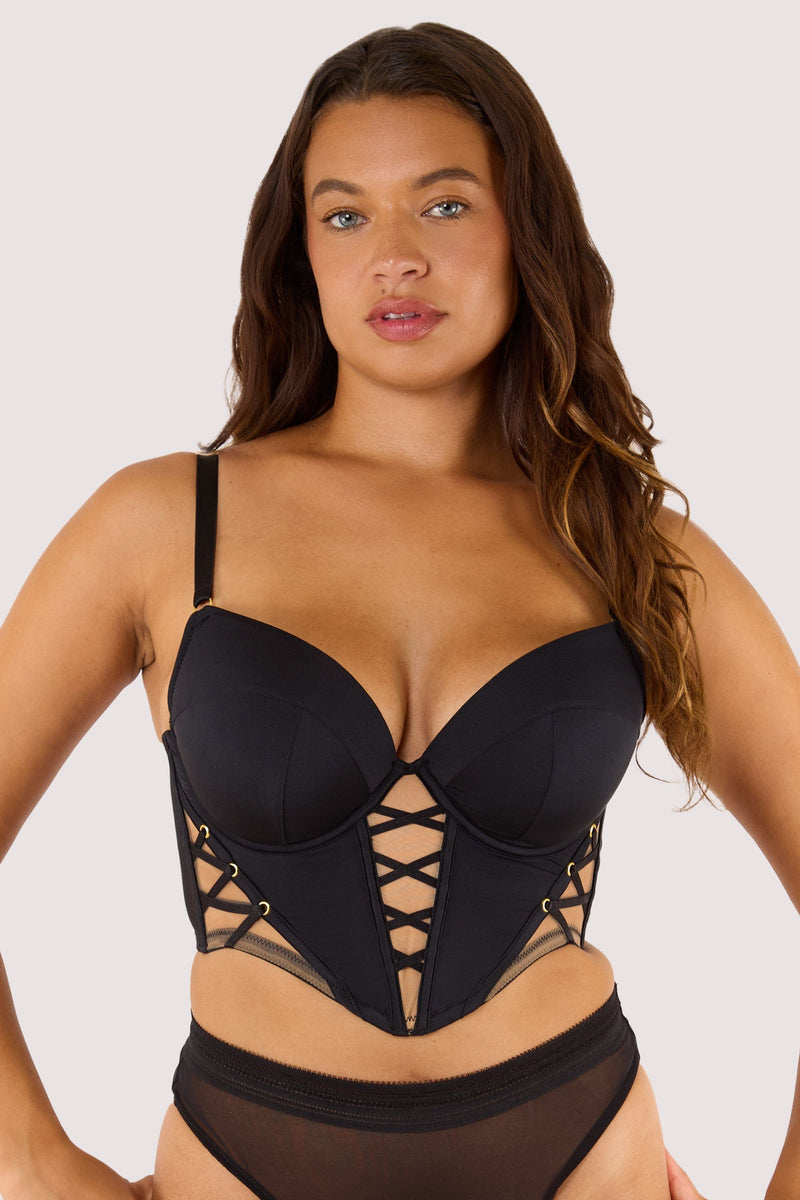 Model wears black lace-up boned bustier with shoulder straps and underwire cups