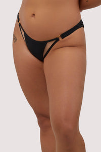 model wears black mid-rise bikini bottoms with nude mesh panels and gold metal rings