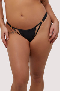 model wears black mid-rise bikini bottoms with nude mesh panels and gold metal rings