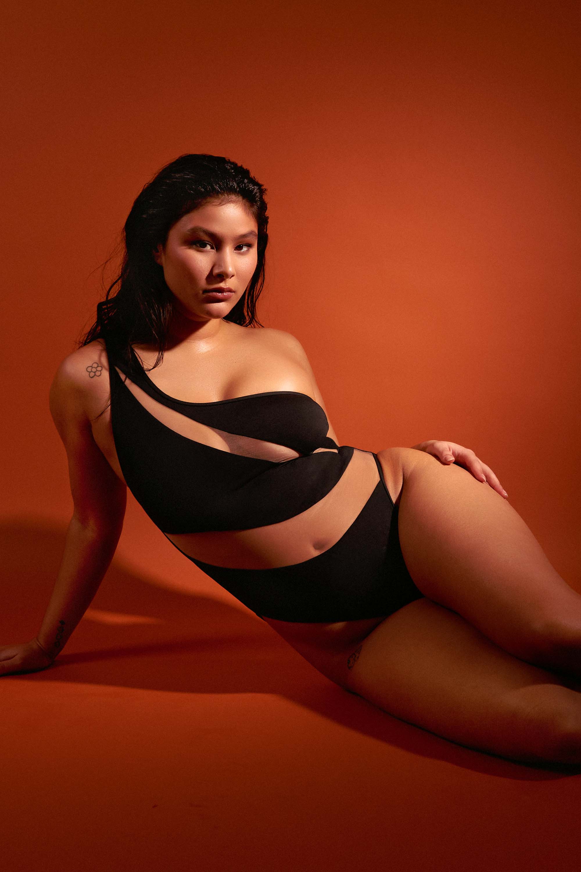 model wears sexy black asymmetrical swimsuit with nude mesh panels