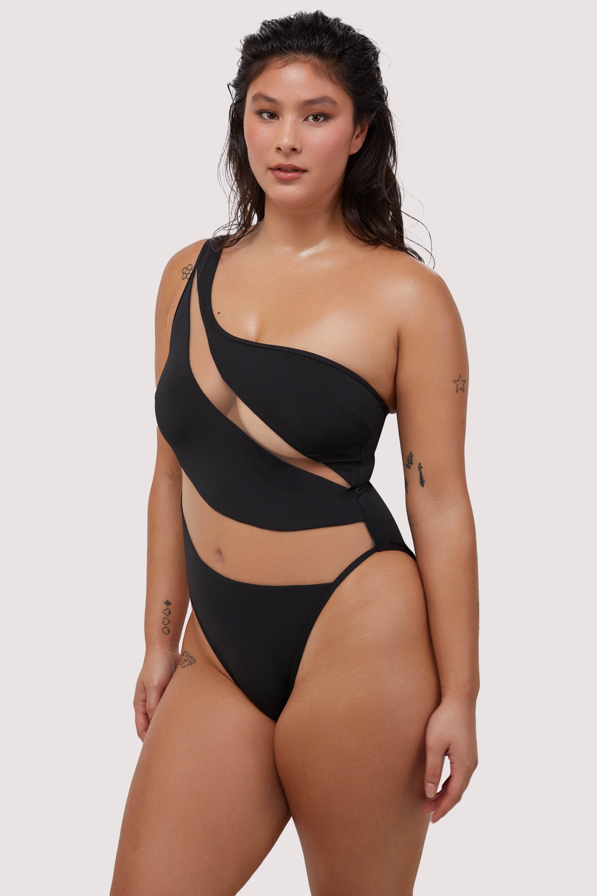 model wears sexy black asymmetrical swimsuit with nude mesh panels