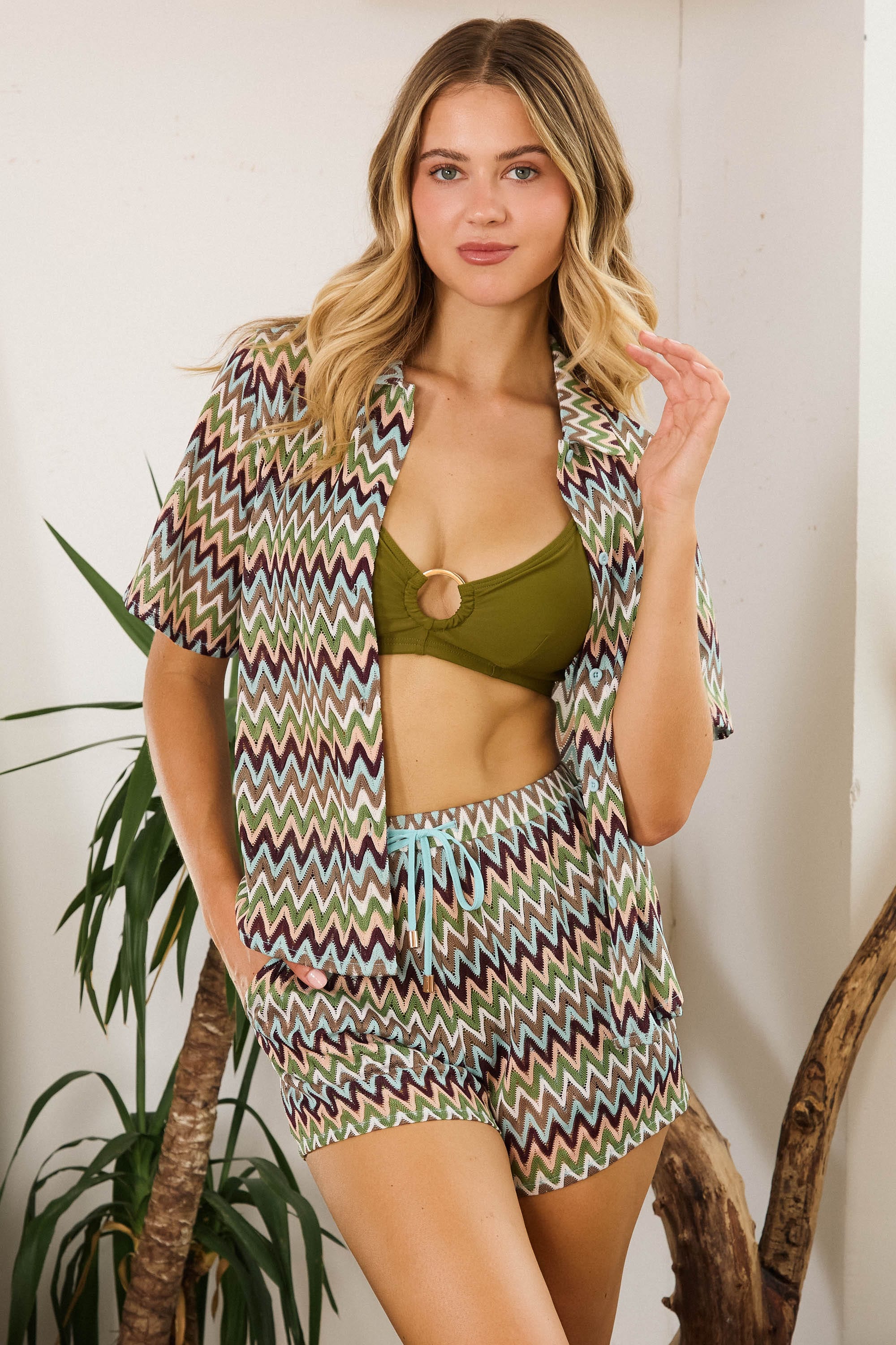 Model in a green bikini top and Kalahari Khaki Zig Zag Crochet Beach Shorts, showcasing a relaxed bohemian style.